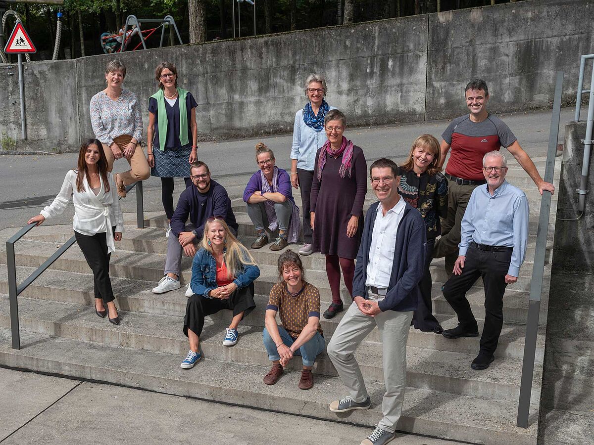 Das Team der Fachbereiche, das sind 14 Frauen und Männer, steht draussen in zwei Reihen für ein neutrales, aber auch fröhliches Gruppenbild zusammen.